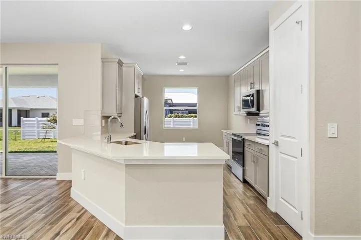 Kitchen with sink, hardwood / wood-style flooring, stainless steel appliances, and gray cabinets