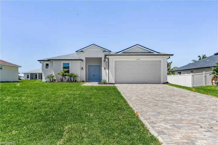 Ranch-style home featuring a garage and a front lawn