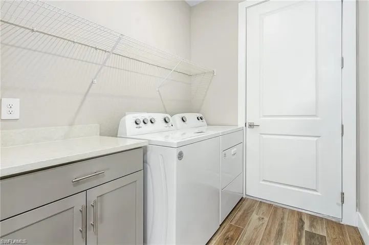Clothes washing area with light hardwood / wood-style floors and washing machine and dryer