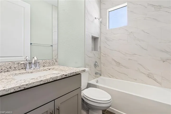 Full bathroom featuring vanity, tiled shower / bath combo, and toilet