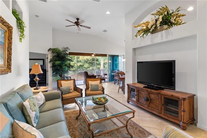 Living room with light tile patterned floors, ceiling fan, high vaulted ceiling, and recessed lighting