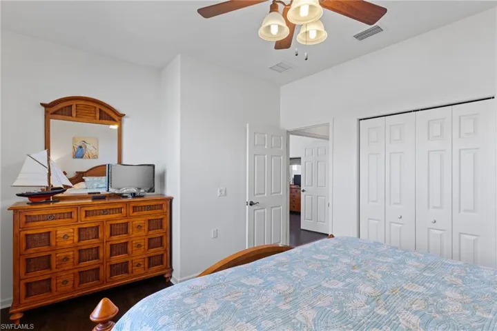 Bedroom with dark wood-type flooring, a ceiling fan, and a closet