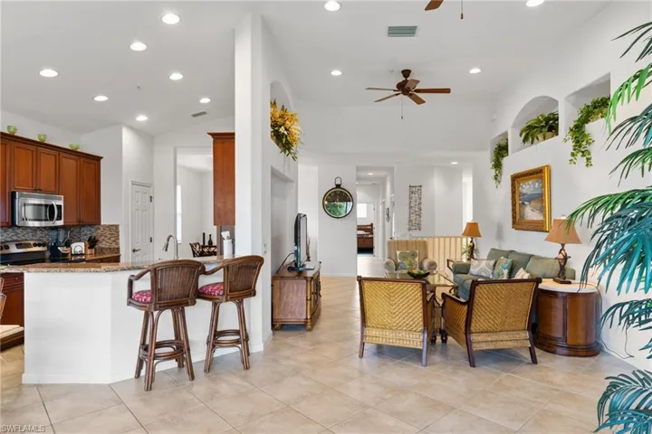 Kitchen featuring a breakfast bar, dark stone counters, backsplash, recessed lighting, and appliances with stainless steel finishes