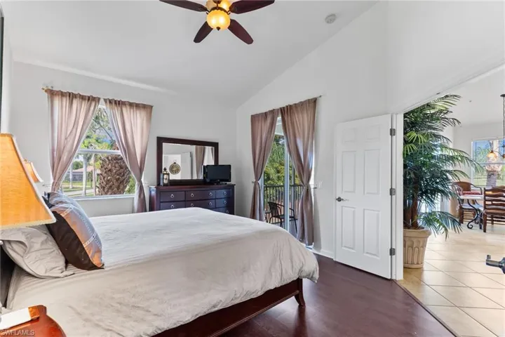 Bedroom featuring dark wood-type flooring, a ceiling fan, access to outside, and high vaulted ceiling