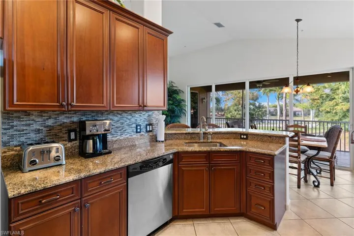Kitchen with a peninsula, dishwasher, light stone countertops, light tile patterned flooring, and lofted ceiling