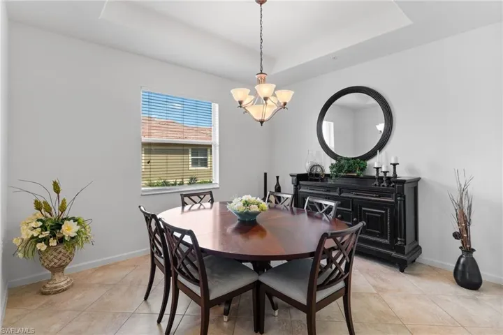 Dining area with a raised ceiling, a chandelier, and light tile patterned flooring