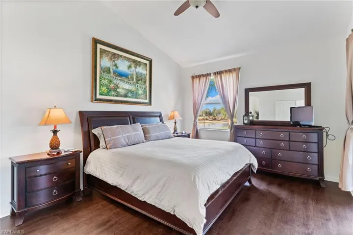 Bedroom with lofted ceiling, dark wood-style floors, and a ceiling fan