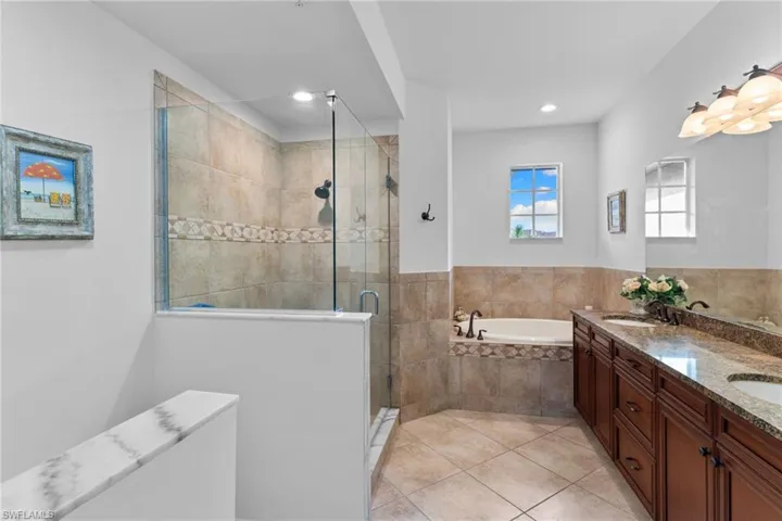 Bathroom featuring double vanity, a bath, a shower stall, and light tile patterned flooring
