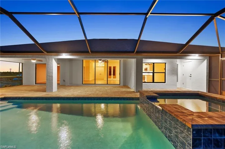 Rear view of property featuring a ceiling fan, a patio, and glass enclosure