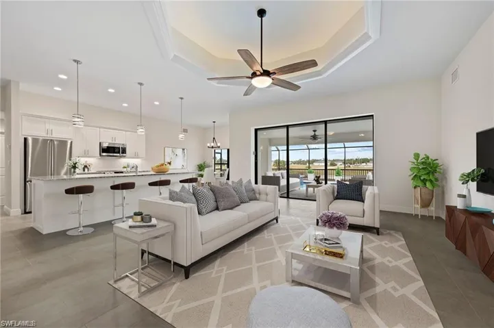 Living room featuring a ceiling fan, recessed lighting, and a raised ceiling