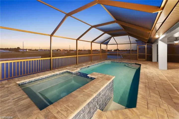 View of pool featuring a patio area, a pool with connected hot tub, glass enclosure, and a ceiling fan