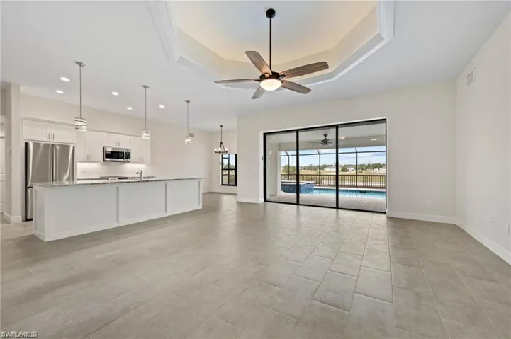 Unfurnished living room featuring a ceiling fan, recessed lighting, and a raised ceiling