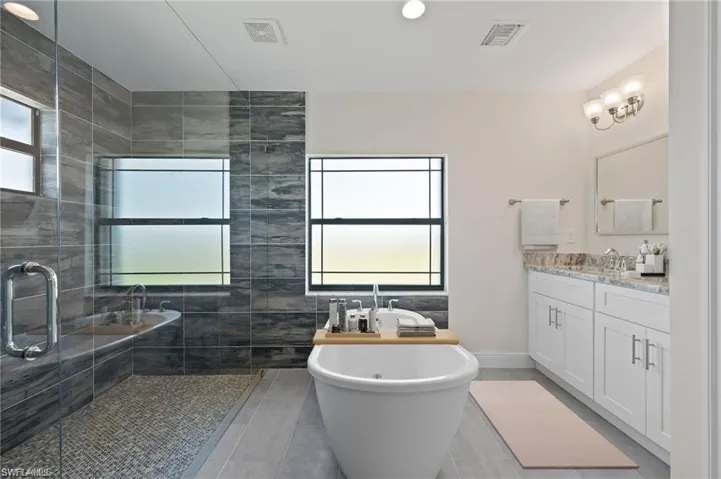 Bathroom with vanity, a freestanding bath, tiled shower, and tile patterned flooring