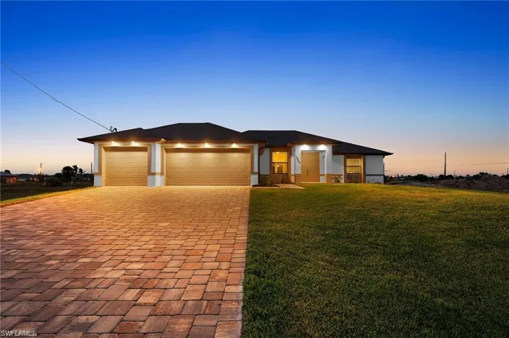 Prairie-style home with decorative driveway, a lawn, stucco siding, and a garage