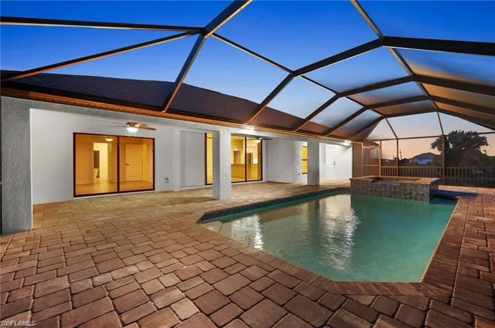View of swimming pool with a patio area, a pool with connected hot tub, and glass enclosure