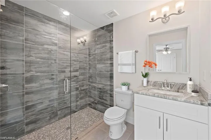 Full bath with vanity, a shower stall, tile patterned flooring, and ceiling fan