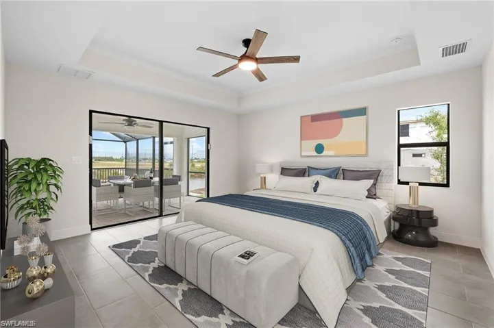 Bedroom featuring a tray ceiling, access to outside, light tile patterned floors, and a ceiling fan