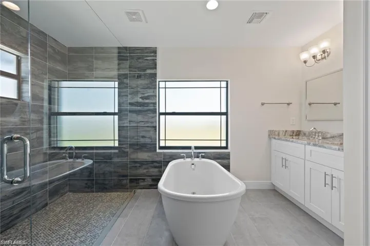 Bathroom featuring vanity, a freestanding tub, tile patterned floors, and a tile shower