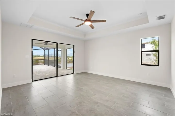 Spare room featuring a tray ceiling, healthy amount of natural light, a ceiling fan, and crown molding