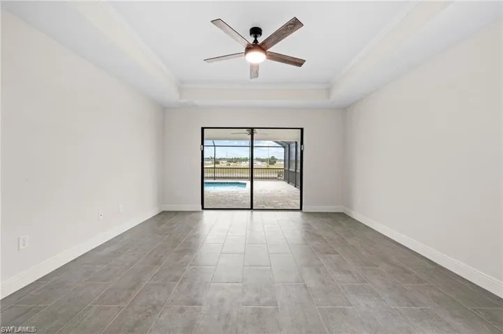 Spare room featuring a raised ceiling, ceiling fan, and crown molding