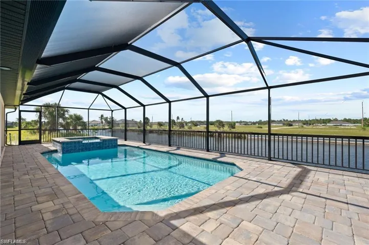 View of pool with a patio, a pool with connected hot tub, a water view, and a lanai