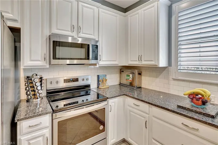 Kitchen featuring white cabinetry and appliances with stainless steel finishes