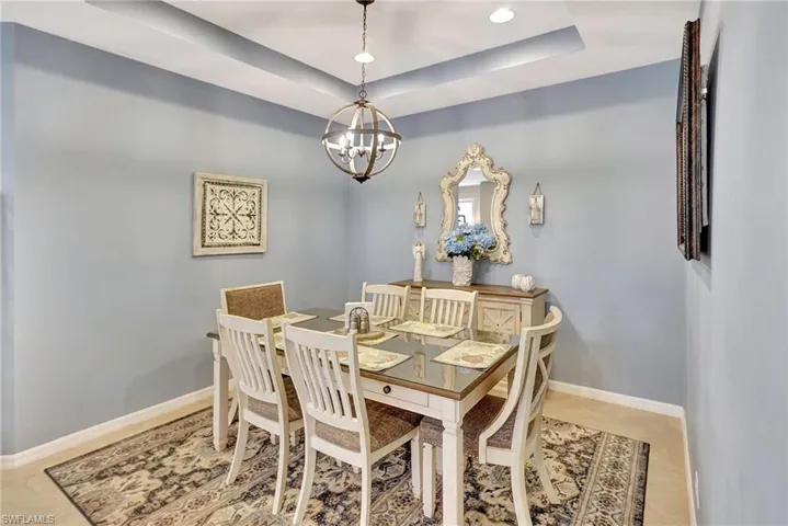 Dining area featuring a chandelier, recessed lighting, baseboards, and a raised ceiling