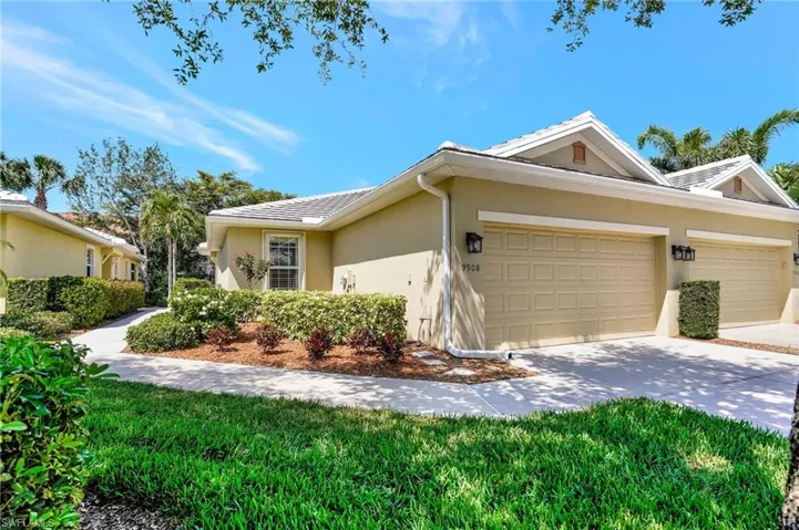 View of side of home with stucco siding, driveway, an attached garage, a tile roof, and a yard