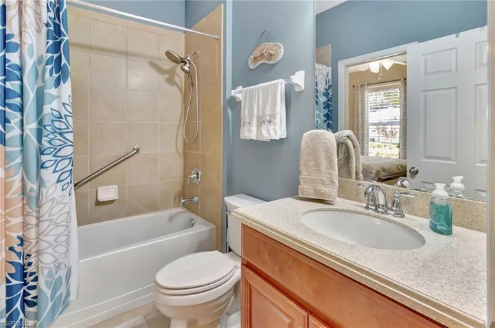 Bathroom with shower / bath combo with shower curtain, vanity, and toilet