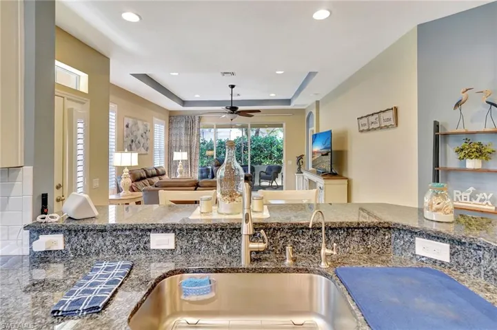 Kitchen with ceiling fan, visible vents, recessed lighting, dark stone countertops, and a raised ceiling