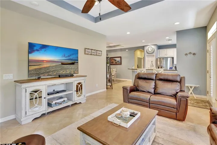 Living room featuring light tile patterned floors, arched walkways, a ceiling fan, recessed lighting, and baseboards