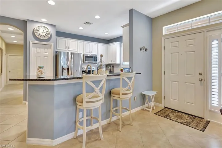 Kitchen featuring dark stone countertops, a peninsula, light tile patterned flooring, a breakfast bar area, and appliances with stainless steel finishes
