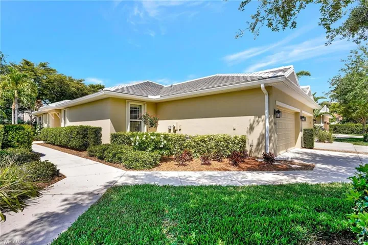 View of side of home with a garage, driveway, stucco siding, and a tiled roof