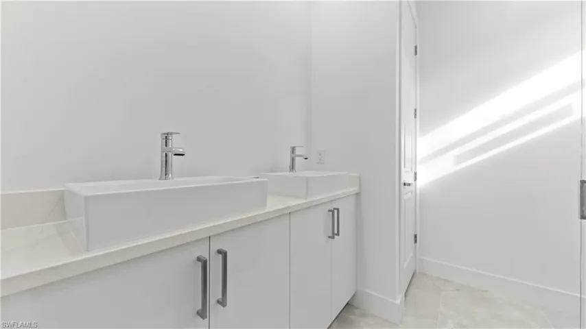Bathroom featuring double vanity and light tile patterned floors