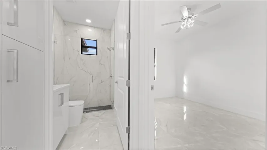 Bathroom featuring light marble finish floors, a marble finish shower, a ceiling fan, vanity, and recessed lighting