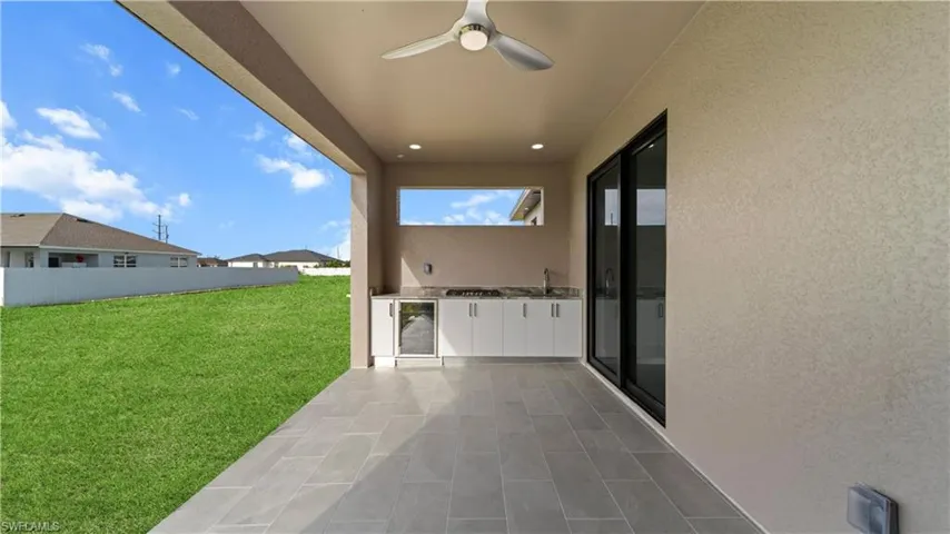 View of patio with ceiling fan, an outdoor kitchen, and beverage cooler