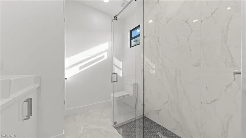 Full bath with a marble finish shower, light marble finish flooring, and vanity