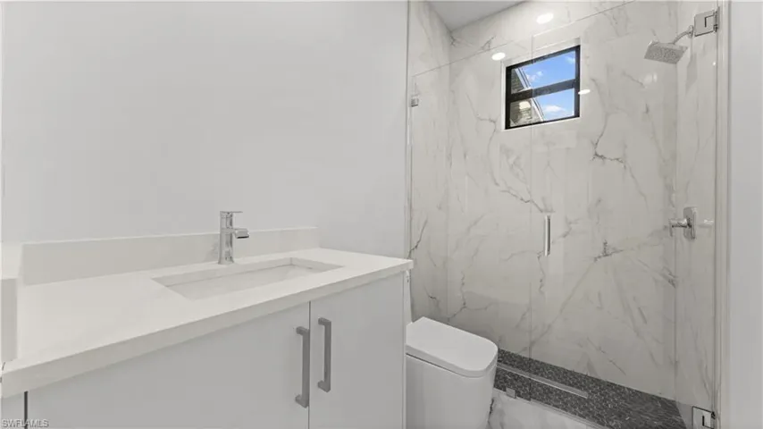 Full bath featuring vanity and a marble finish shower