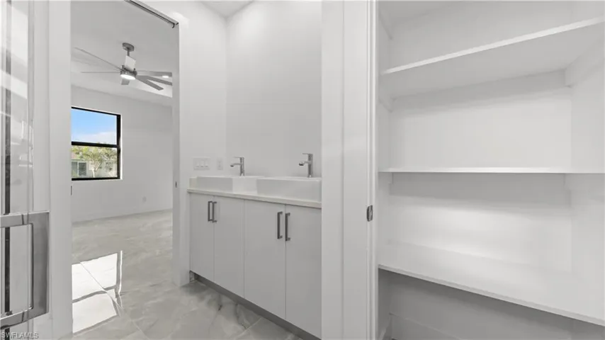Bar featuring light marble finish flooring, a ceiling fan, and light countertops
