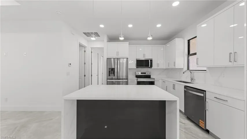 Kitchen featuring white cabinets, appliances with stainless steel finishes, pendant lighting, a kitchen island, and recessed lighting
