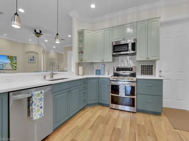 Kitchen with ceiling fan, sink, hanging light fixtures, stainless steel appliances, and decorative backsplash