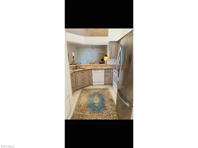 Kitchen with white appliances, open floor plan, light tile patterned floors, and light countertops