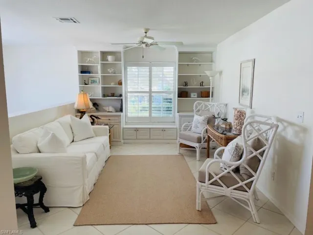 Living area featuring light tile patterned floors, ceiling fan, and built in features