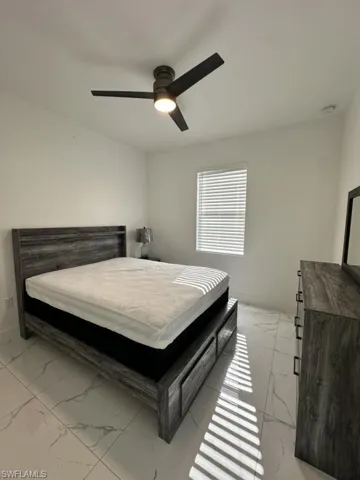 Bedroom featuring a ceiling fan and light marble finish flooring