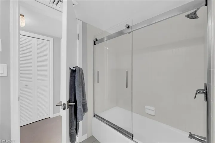 Bathroom with combined bath / shower with glass door and a closet