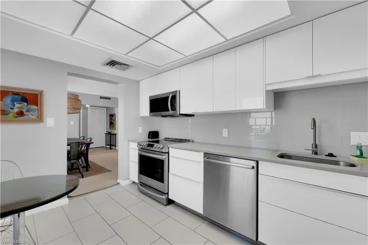 Kitchen with stainless steel appliances, white cabinets, modern cabinets, and backsplash