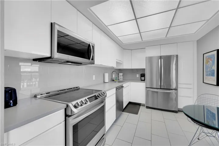 Kitchen featuring stainless steel appliances, light countertops, white cabinets, modern cabinets, and decorative backsplash
