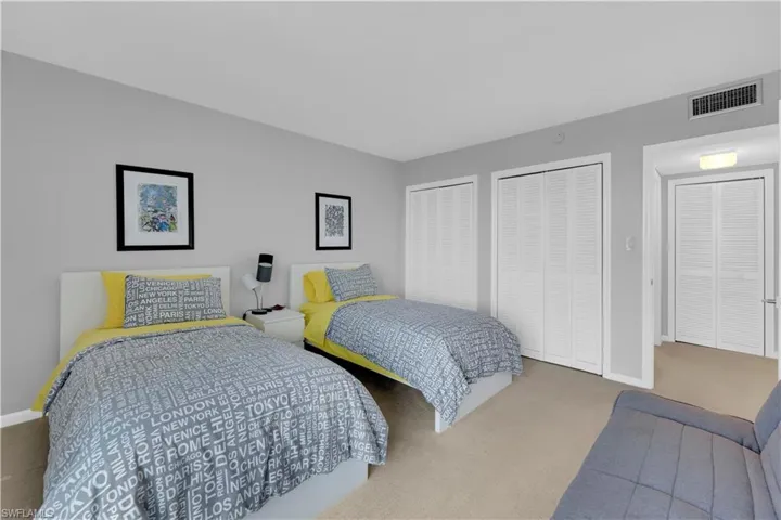 Carpeted bedroom with two closets and baseboards