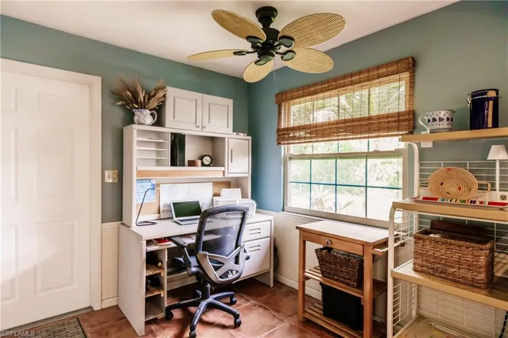 Office with dark tile patterned flooring and ceiling fan