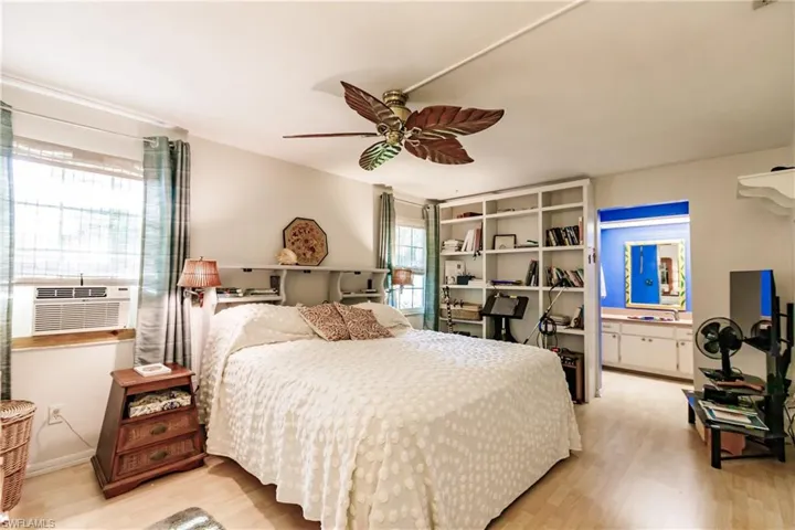 Bedroom with cooling unit, light hardwood / wood-style flooring, ensuite bath, and ceiling fan
